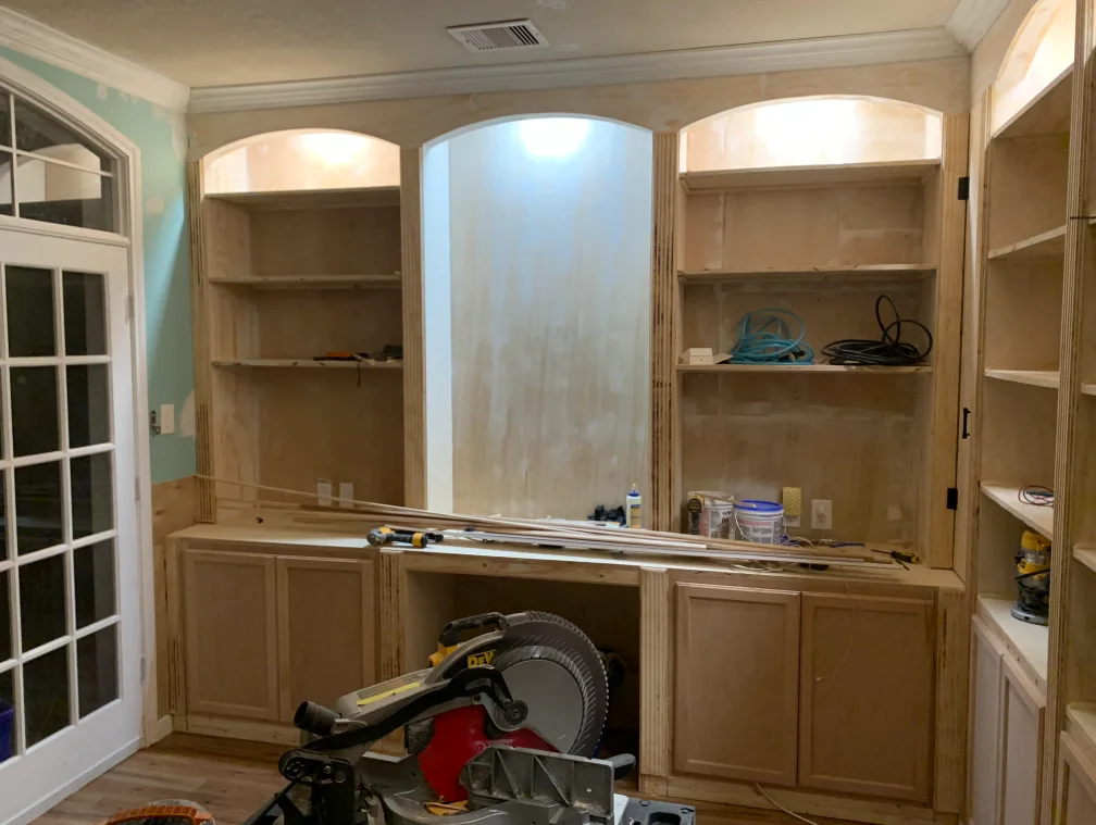 Built-in library cabinets and shelves continuing around a room during construction.